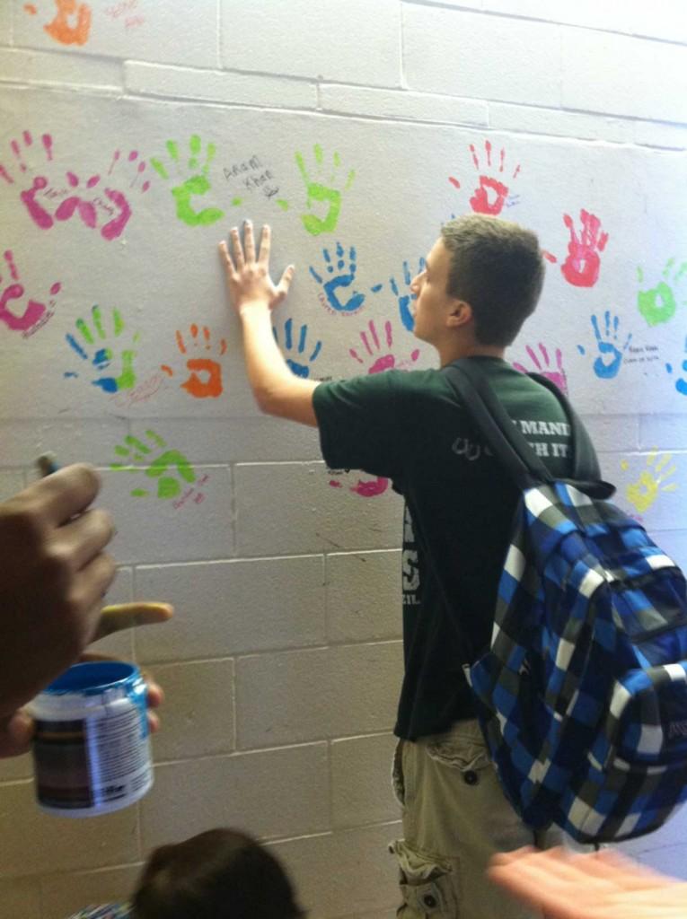 Junior+Phillip+Jenkins+participates+in+awarness+week+by+placing+his+hand+print+on+the+wall.+
