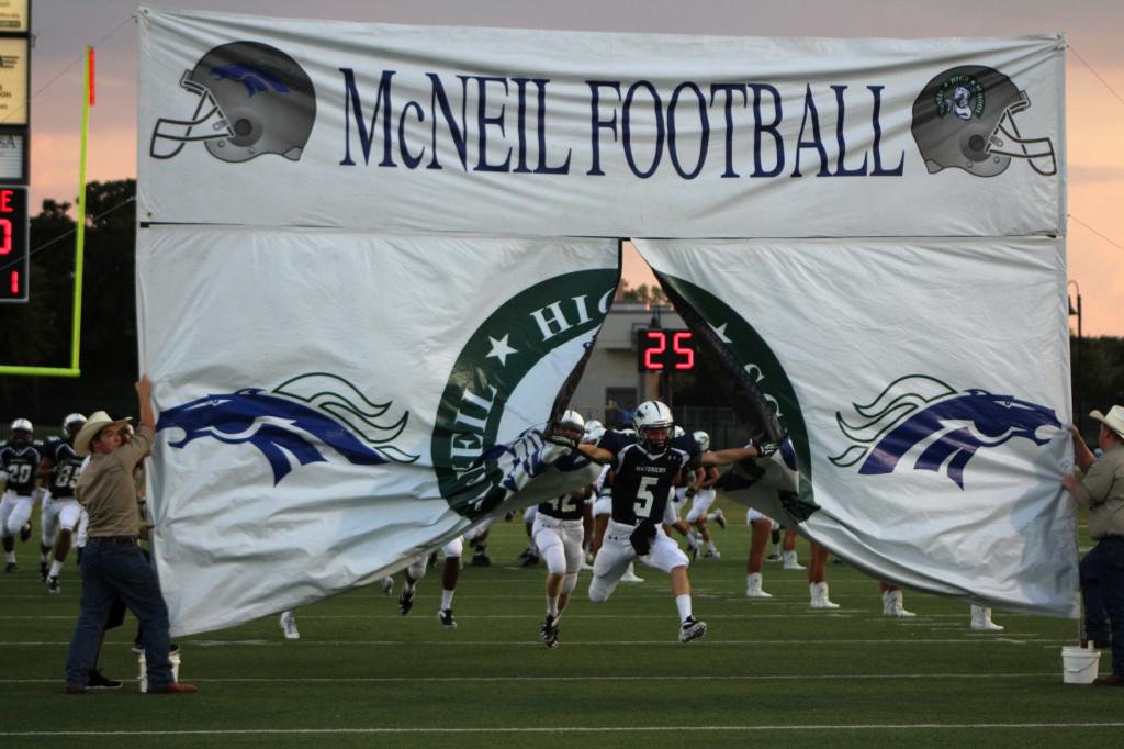 Colton Russell leads the team out on the field as the Mavs break through the opening banner ready to play. 