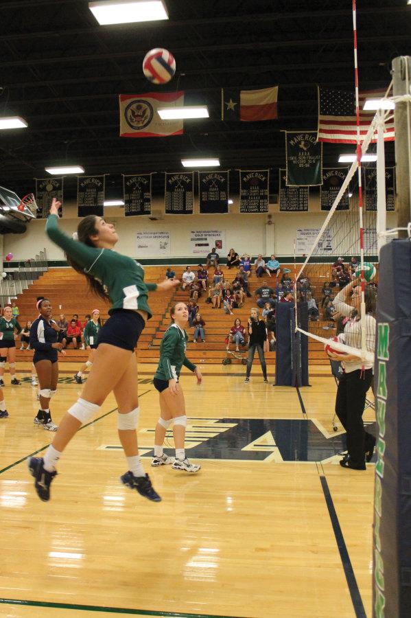 Practicing before the match against the Lady Dragons, Katie Silguero (12) goes up for a spike.