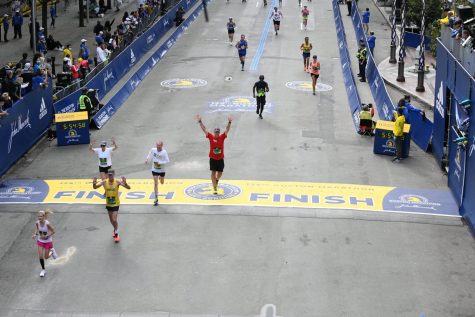 Alden Balmer raises his hands as he crosses the finish line of the Boston Marathon on Oct. 11. 