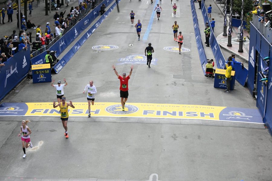 Alden+Balmer+raises+his+hands+as+he+crosses+the+finish+line+of+the+Boston+Marathon+on+Oct.+11.+