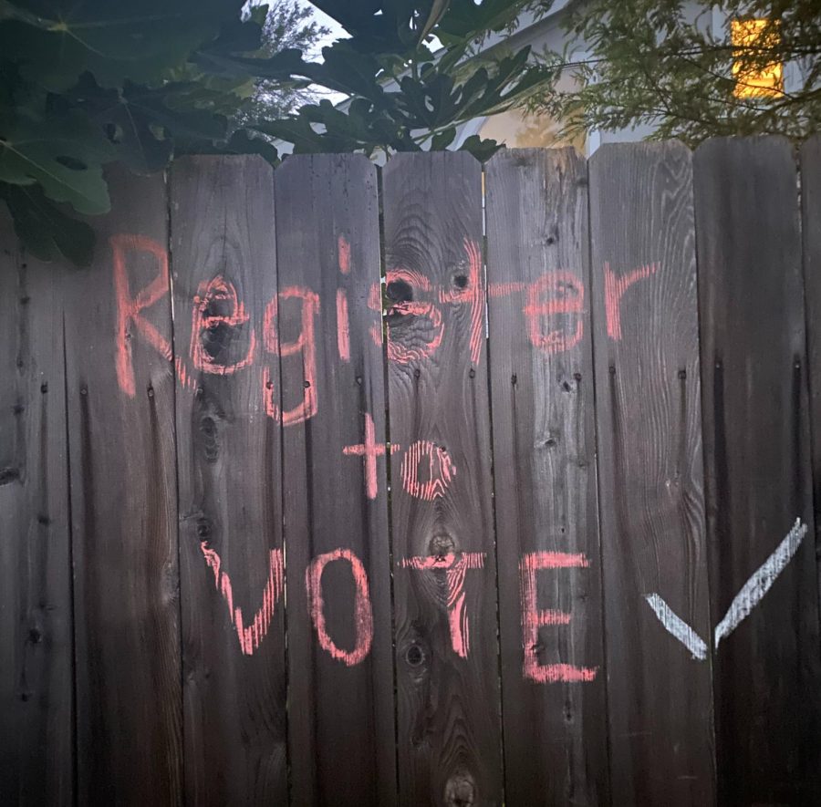 A sign written in chalk reminds people to register to vote.
