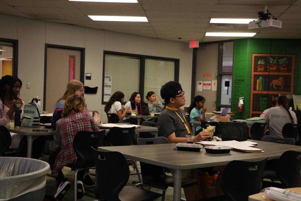 Students eat lunch while paying attention to the library's presentation. 