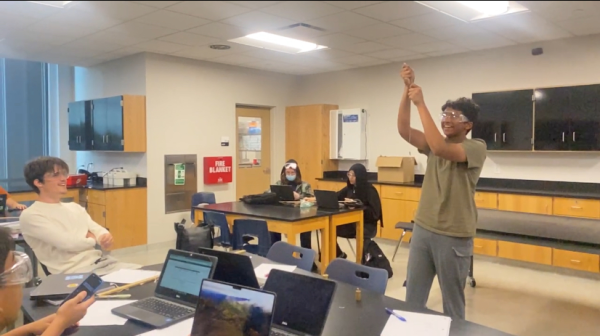 Junior William Curp watching as sophomore Gawdham Ramesh spins a string with a rubber stopper to show centripetal force.