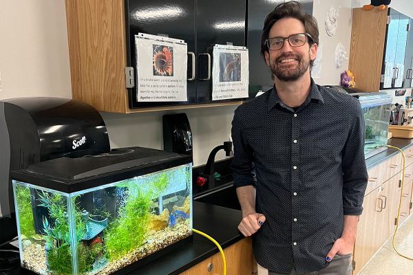 Teacher Romano next to his fish tank.