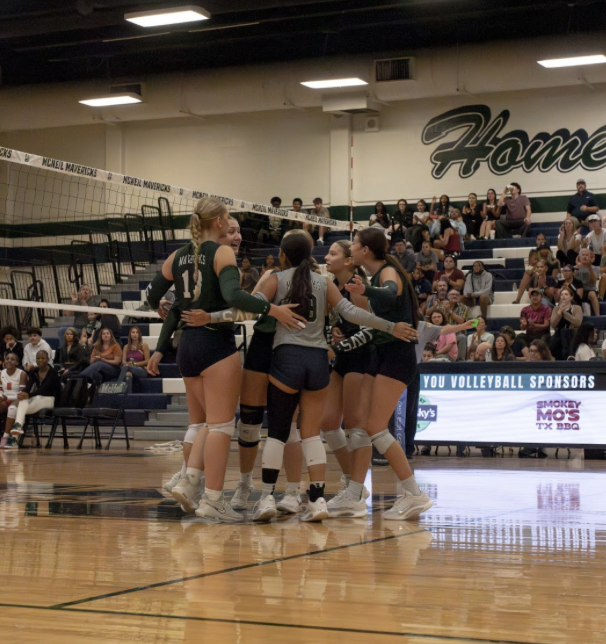 The Lady Mavs gather at the net to celebrate the point and discuss the next play.