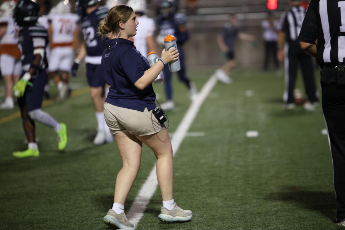Student athletic trainer Halynd Golden runs onto the field during a timeout to hand water to the referees. 